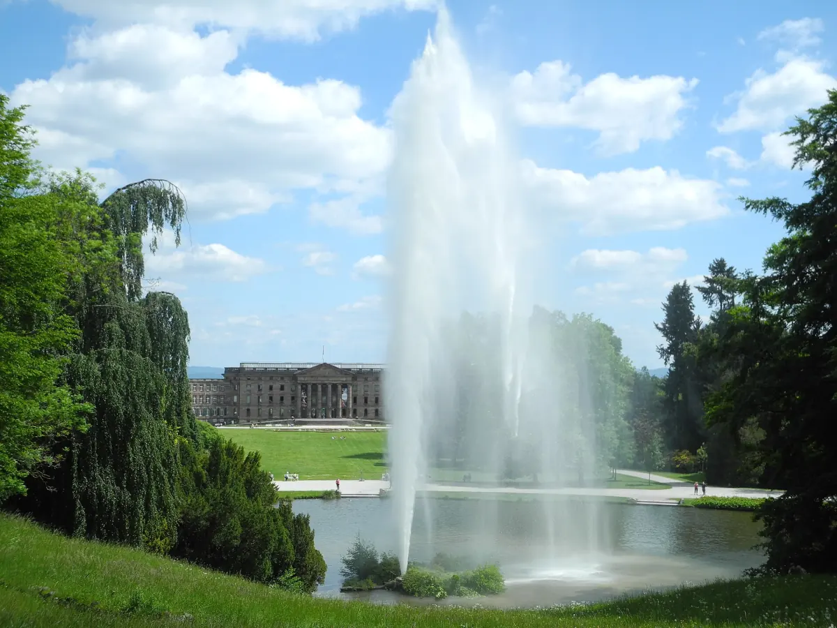 Die Große Fontäne steigt aus dem Fontänenteich, im Hintergrund liegt Schloss Wilhelmshöhe.