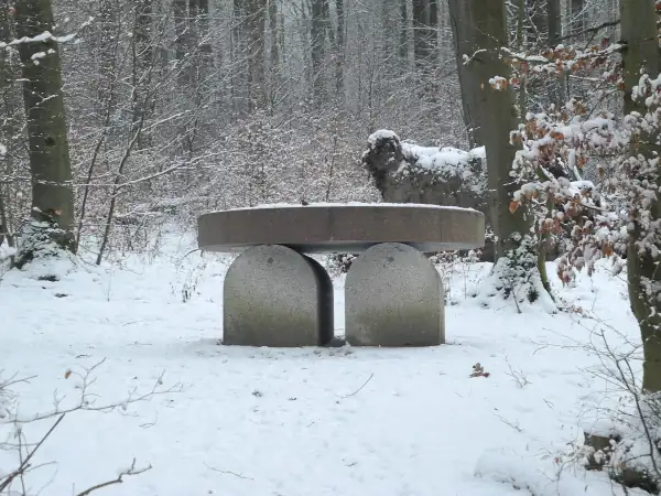 Ein steinernes Grabmal in Tischform steht im verschneiten Wald der Künstler-Nekropole bei Kassel.