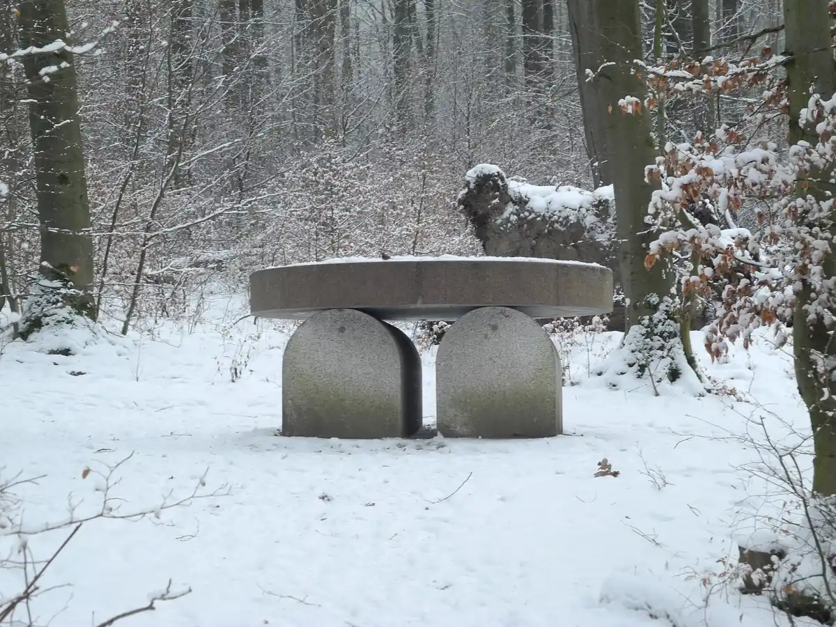 Ein steinernes Grabmal in Tischform steht im verschneiten Wald der Künstler-Nekropole bei Kassel.