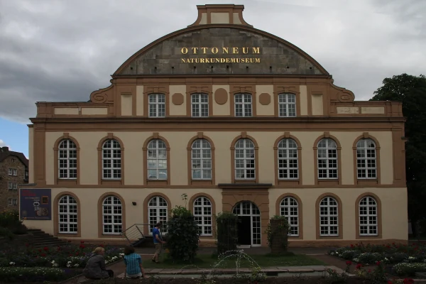 Die Fassade des Ottoneums mit goldener Aufschrift „Naturkundemuseum“ unter bewölktem Himmel.