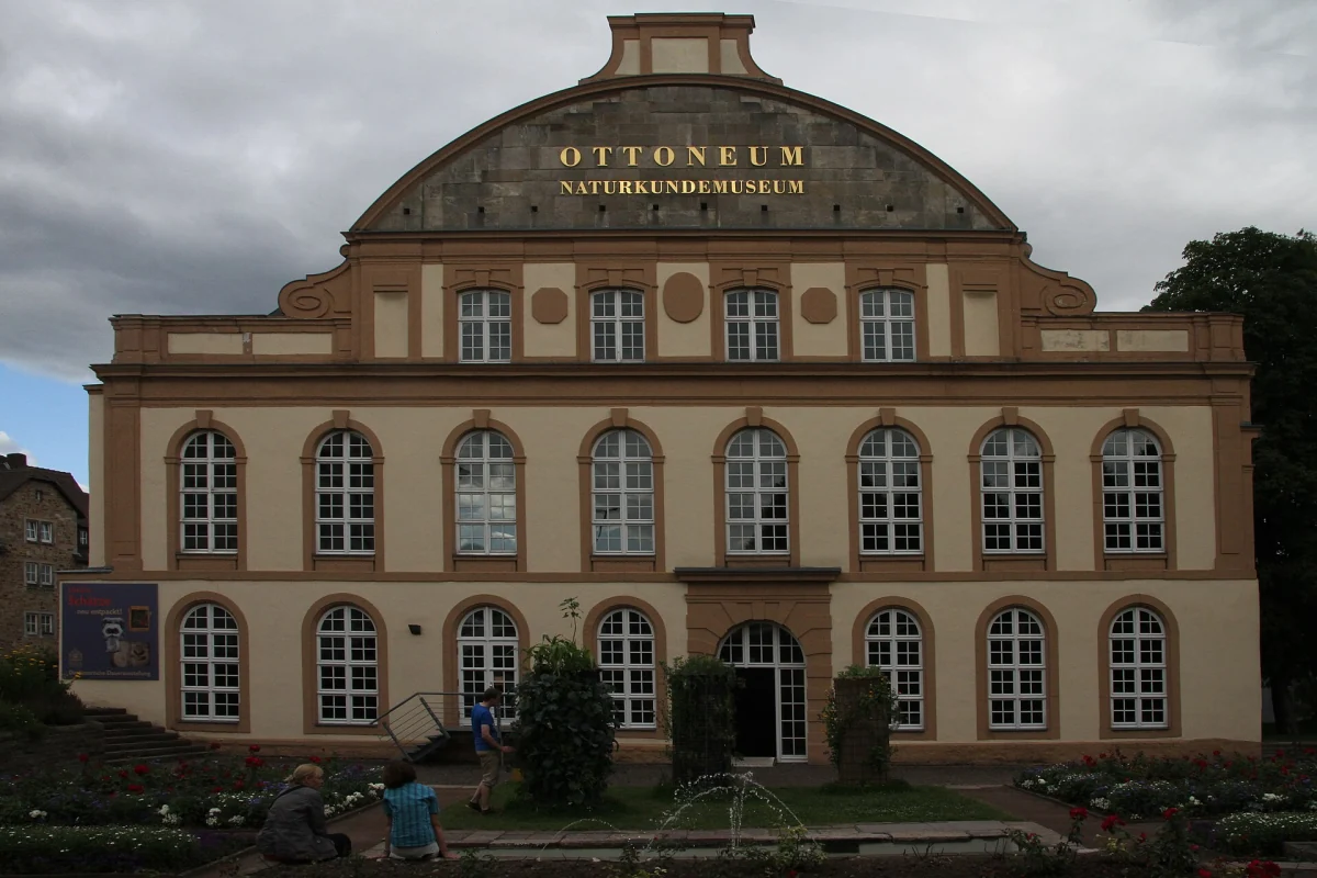 Die Fassade des Ottoneums mit goldener Aufschrift „Naturkundemuseum“ unter bewölktem Himmel.