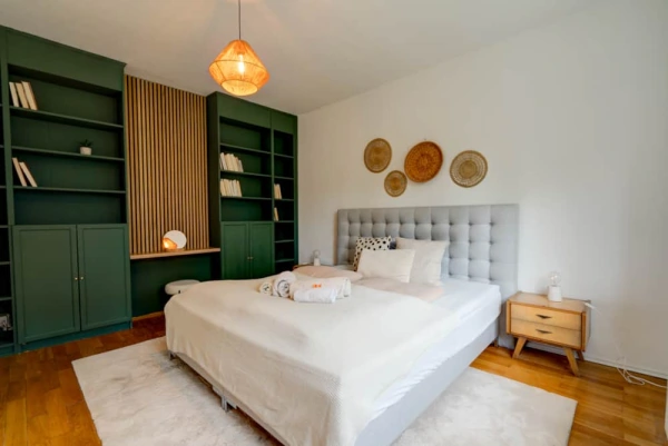 Helles Schlafzimmer der Ferienwohnung Herkules mit großem Bett und grünen Einbauregalen.