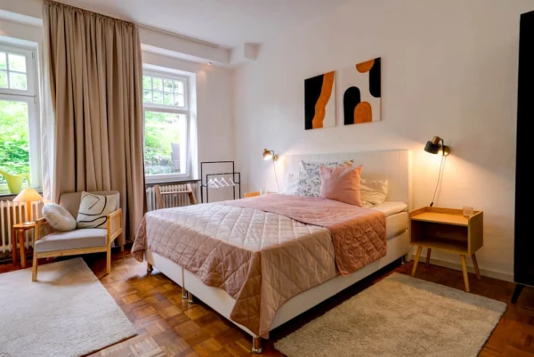 Schlafzimmer der Ferienwohnung Löwenburg mit Parkettboden und großen Fenstern.